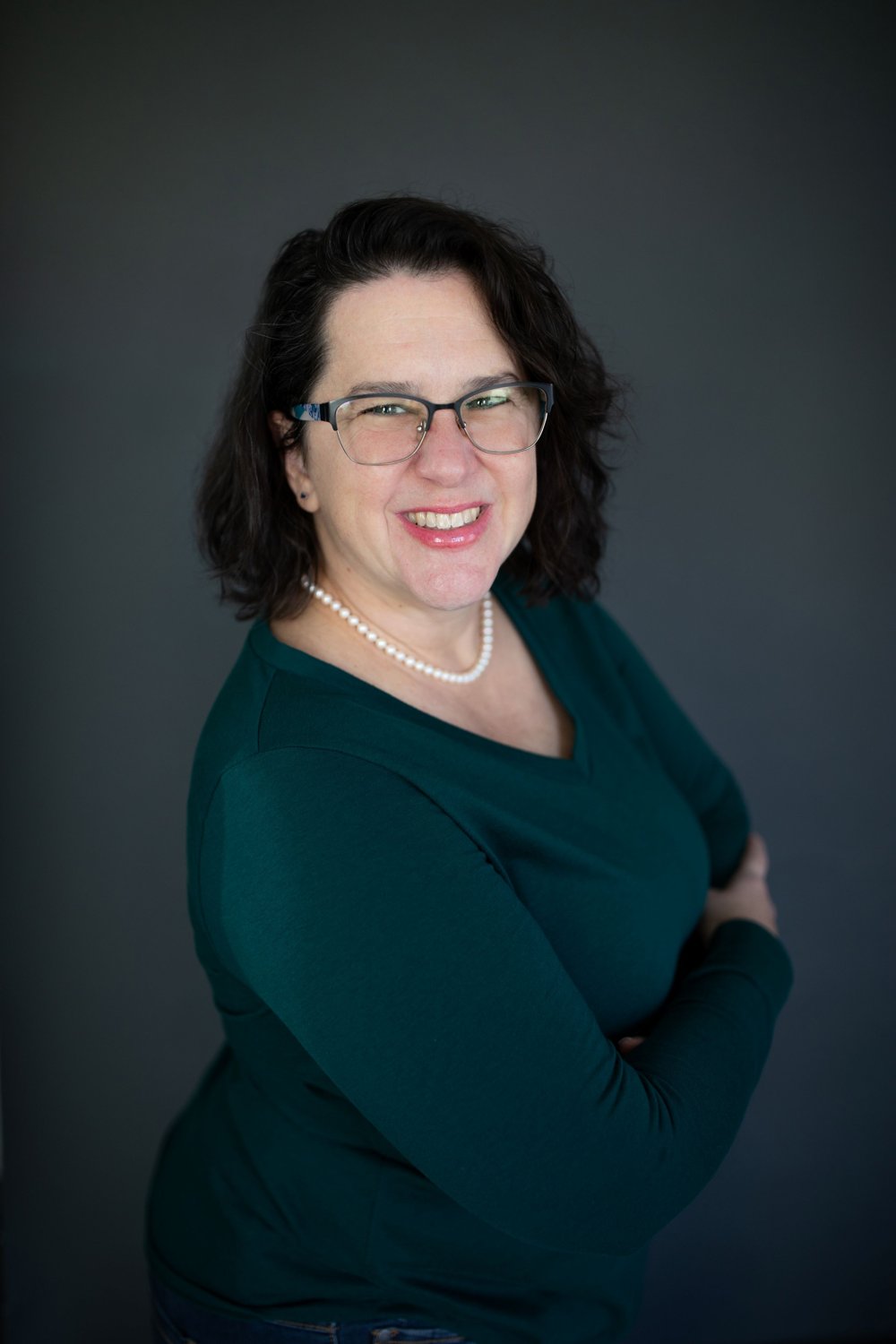 Dawn Parzych, smiling, in a green top against a dark gray backdrop